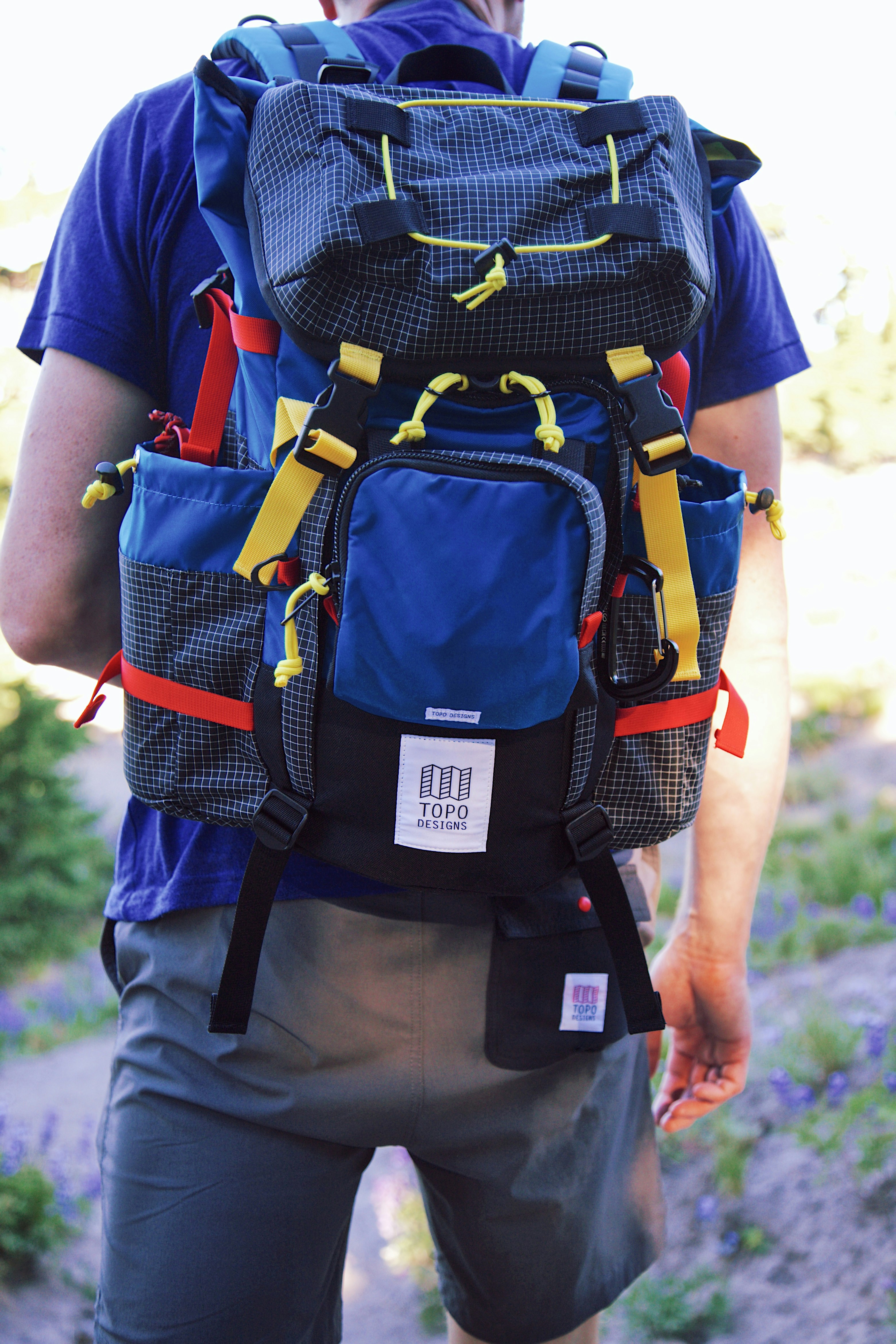 man in red t-shirt carrying black and orange backpack